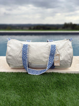 Bolsa de lona de algodón tejido beige con asas de motivos geométricos en color azul y blanco