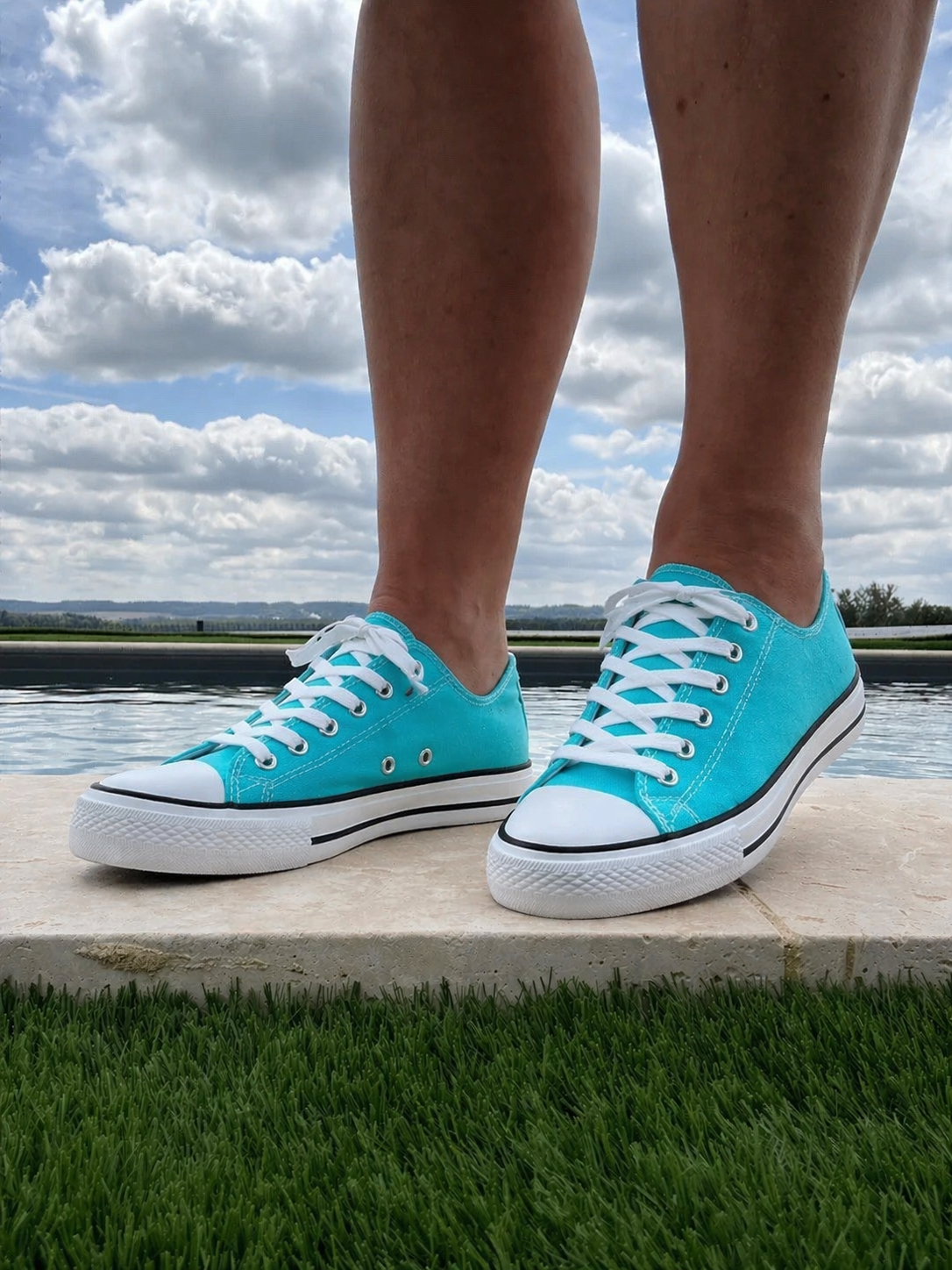 Chaussures Converse turquoise Baskets basses au look néon, lacets blancs et semelle blanche avec liseré noir, portée près d’un plan d’eau.