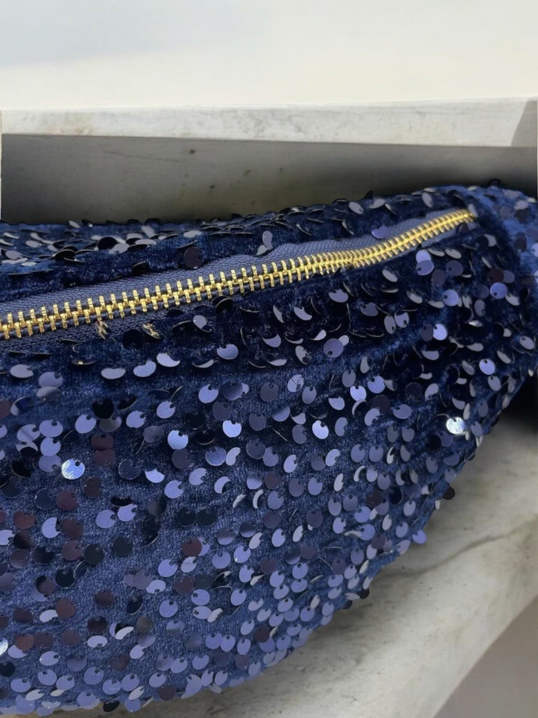 Sac banane bleu marine à paillettes avec zip doré et bandoulière réglable, effet scintillant.