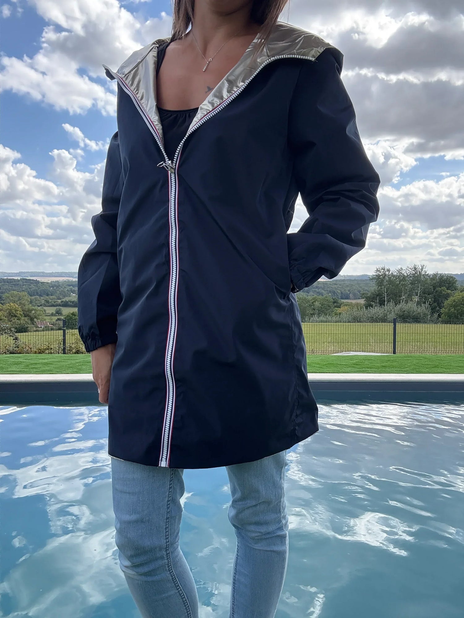 Woman wearing Laura Jo navy raincoat by a pool, outdoor scene, Le Petit Placard style