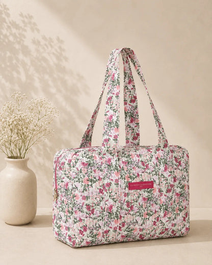 Sac polochon matelassé à imprimé floral rose pivoine et vert sauge sur fond blanc, avec poignées longues.