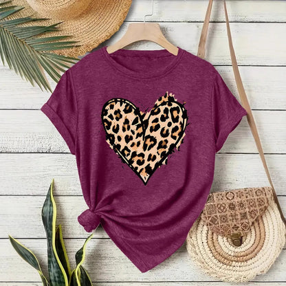 T-shirt femme mauve à col rond avec cœur imprimé Léopard, modèle tendance, nœud latéral sur fond bois.