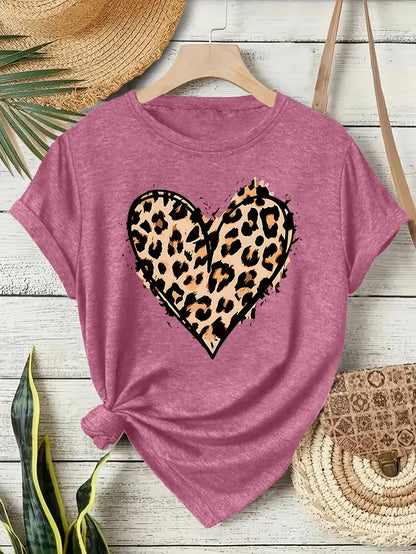 T-shirt rose oversized avec cœur imprimé léopard, nœud latéral sur fond bois et accessoires bohèmes.