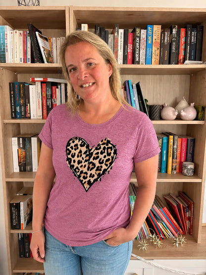 T-shirt rose casual chic avec cœur imprimé léopard, porté par une femme devant une bibliothèque.