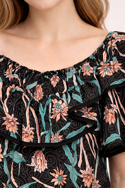 Blouse noire à motif floral pêche et vert avec col volanté et double ruche noir sur les bords.