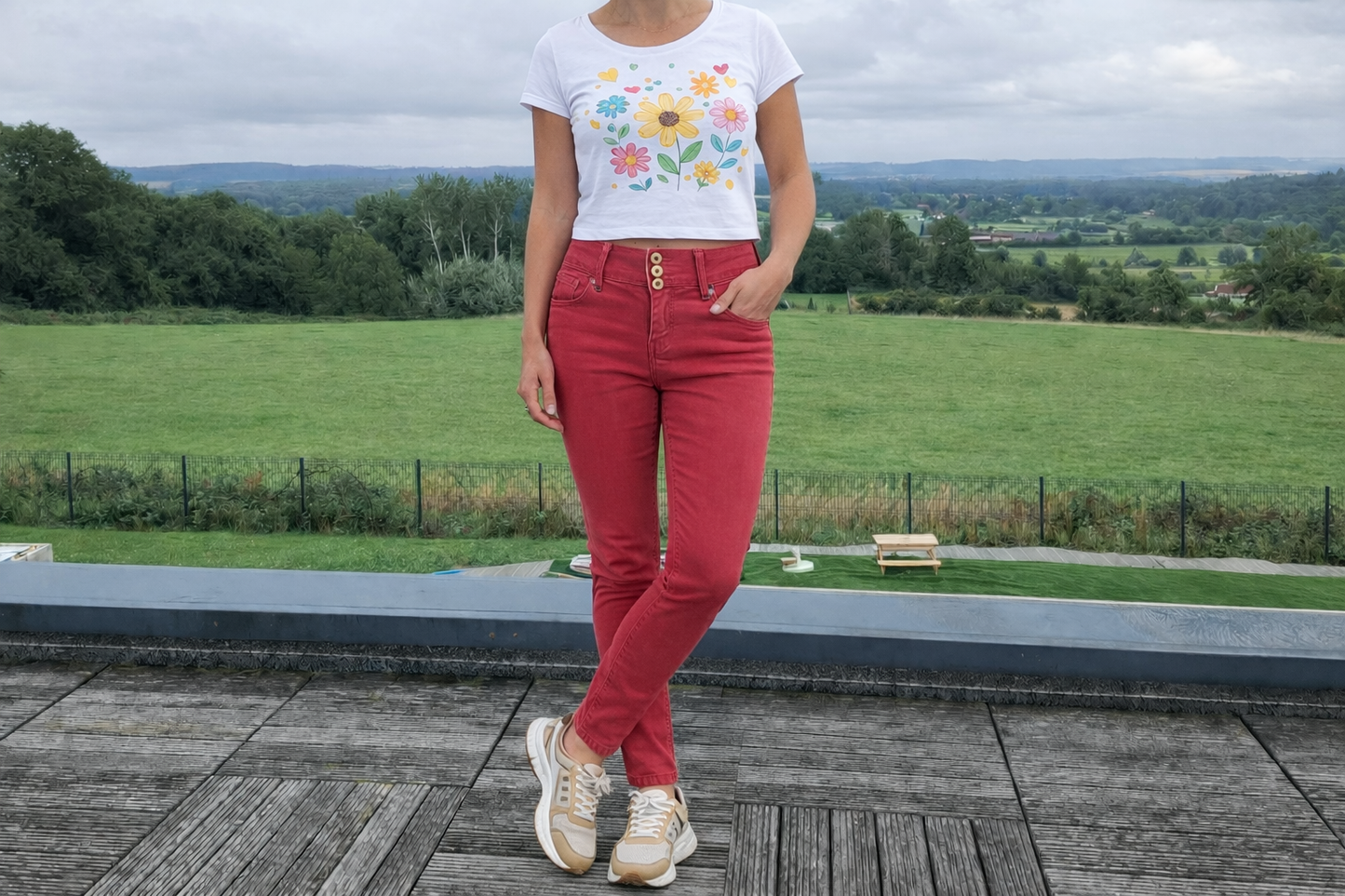 Femme portant un jean skinny taille haute rouge brique de la marque Le Petit Placard, avec un t-shirt floral, vue de face.