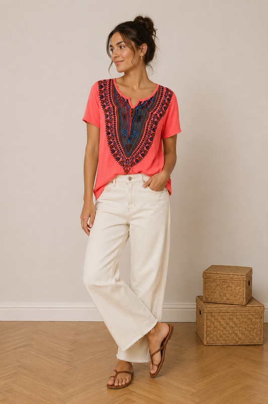 Top Dashiki Corail – Imprimé Ethnique Bleu & Brun Style Boho taille L: T-shirt corail à motif mandala bleu-brun porté avec un pantalon blanc et sandales.