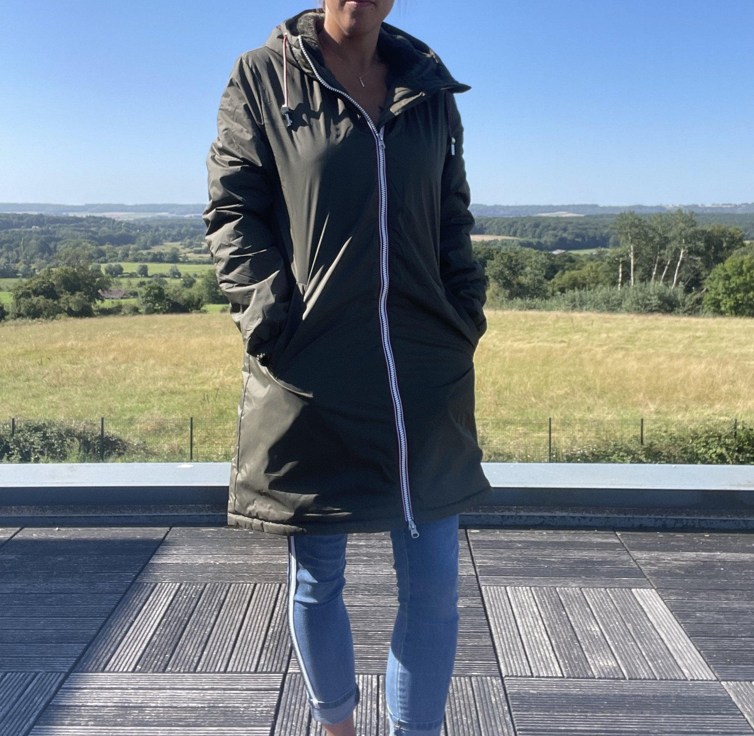 Woman wearing a Laura Jo khaki raincoat from Le Petit Placard, outdoor scenic background