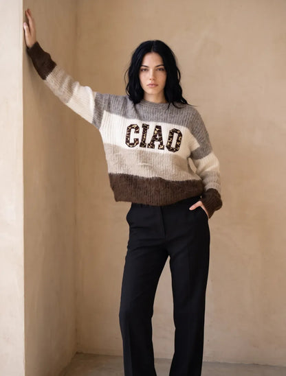 Pull en maille femme CIAO gris marron porté par une modèle debout dans un mur beige, manches longues et logo CIAO sur le torse.