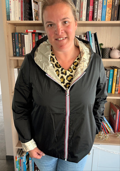Imperméable réversible Laura Jo noir et doré porté par une femme, intérieur doré visible sur le col et les poignets, en bibliothèque.