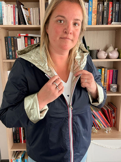 Imperméable réversible court bleu marine doré pour femme, Laura Jo Mi Saison, portée par une femme à l’intérieur près d’une bibliothèque.