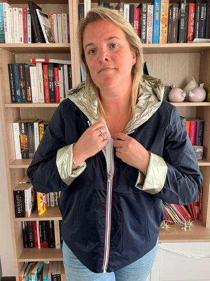 Imperméable réversible court bleu marine doré femme Laura Jo Mi Saison portée par une femme devant une bibliothèque.