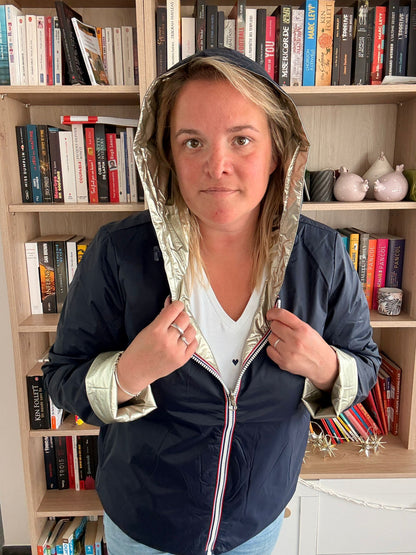 Imperméable réversible court bleu marine doré femme Laura Jo Mi Saison portée par une femme devant une bibliothèque.