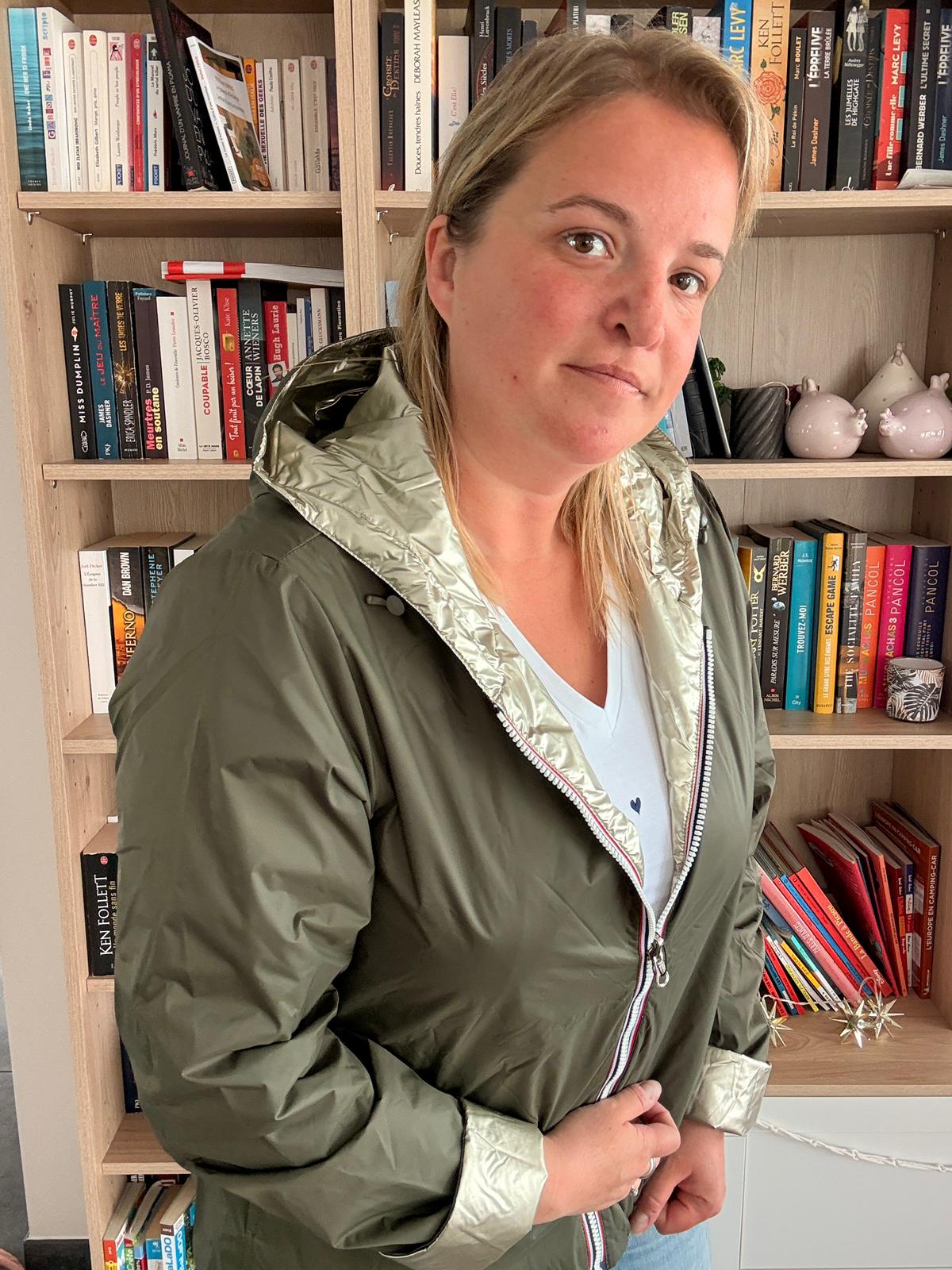 Imperméable réversible court kaki doré femme Laura Jo Mi-Saison portée par une femme debout, bibliothèque en arrière-plan.