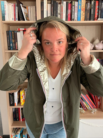 Imperméable réversible court kaki doré femme Laura Jo Mi-Saison porté par une jeune femme dans une bibliothèque, capuche sur la tête.