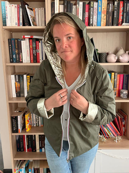 Imperméable réversible court kaki doré pour femme, portée en intérieur par une femme près d'une bibliothèque.