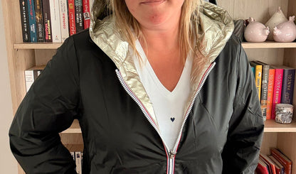 Imperméable reversible court noir doré pour femme, version reversible avec intérieur doré, porté sur un pull blanc.