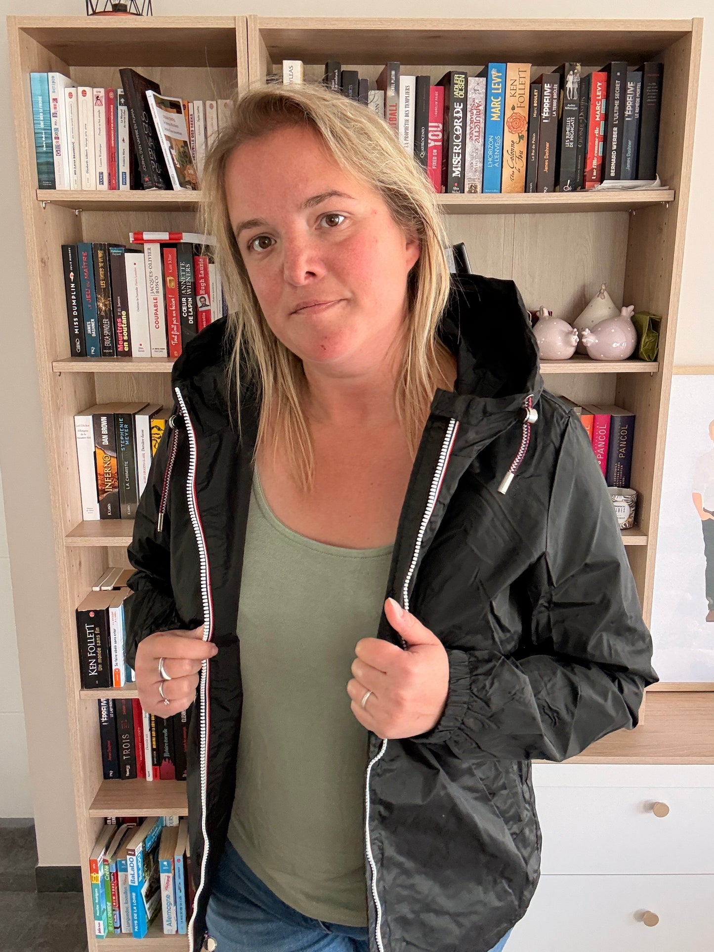 Femme ouvrant l'imperméable court noir Laura Jo à deux mains, doublure intérieure et zip tricolore en évidence
