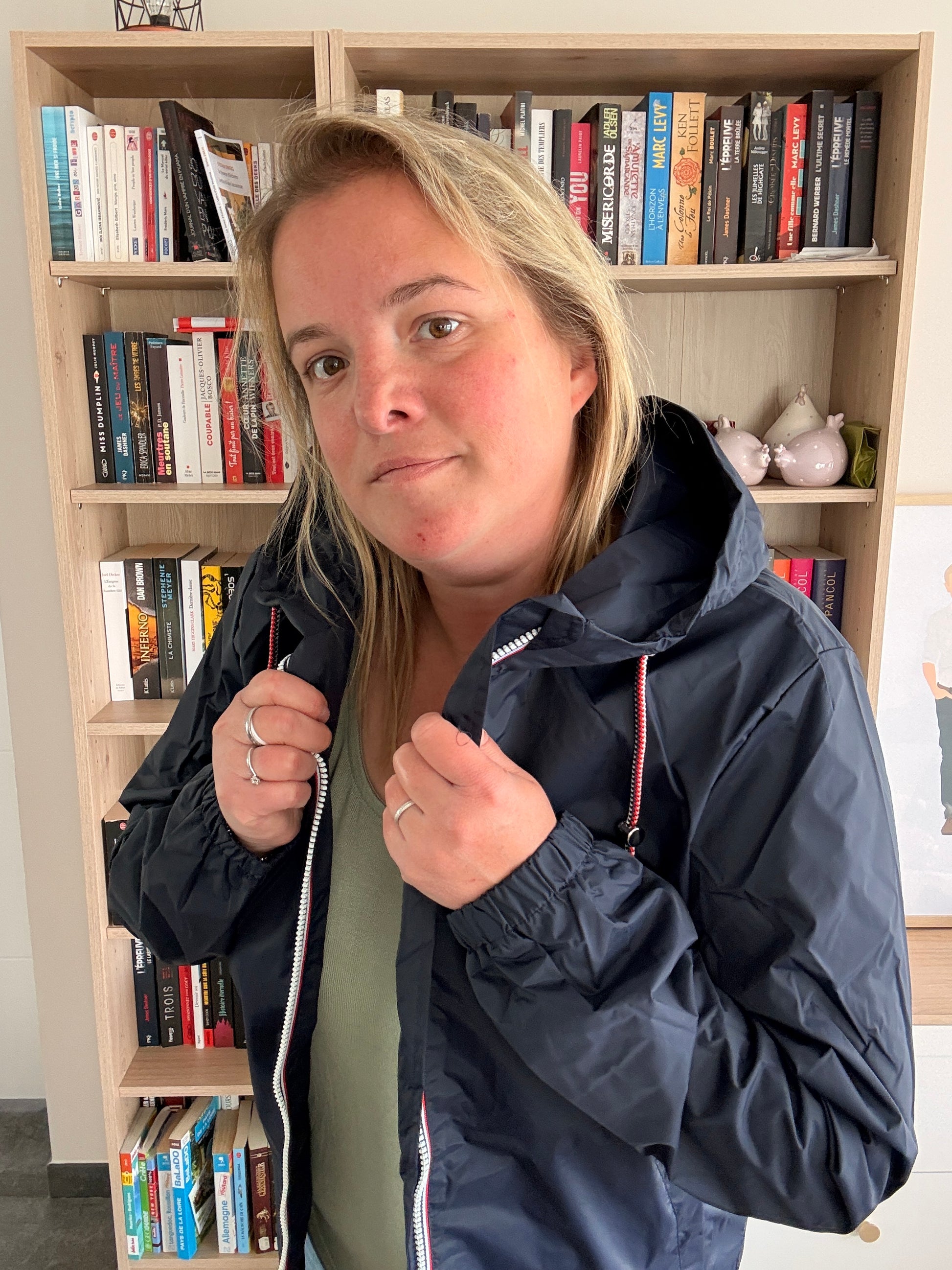 Gros plan sur le col et le zip tricolore de l'imperméable mi-long bleu marine Laura Jo, poignets resserrés visibles