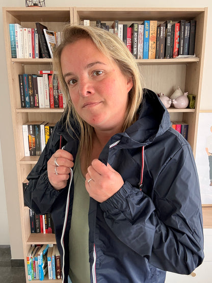 Gros plan sur le col et le zip tricolore de l'imperméable mi-long bleu marine Laura Jo, poignets resserrés visibles