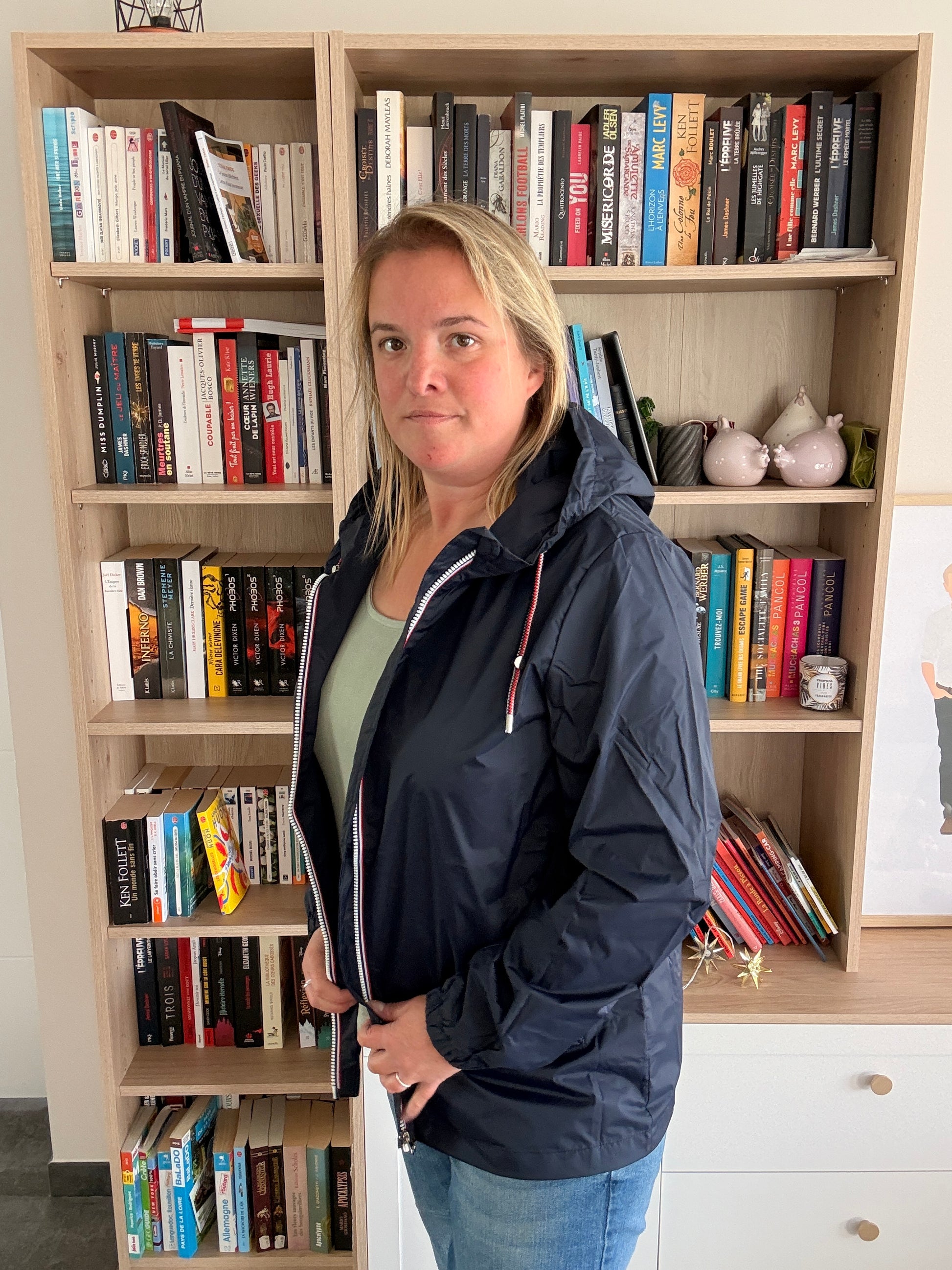 Femme de 3/4 portant l'imperméable mi-long bleu marine Laura Jo, coupe droite et zip tricolore visibles