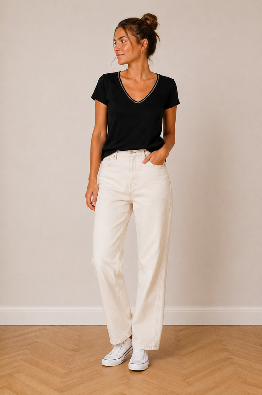 T-shirt Noir Col V avec liseré tressé bicolore porté par une femme, pantalon clair et baskets, look décontracté.