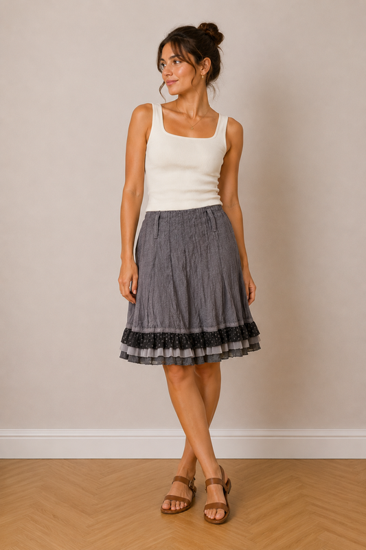 Jupe midi grise à volants pois, coupe évasée, taille S, portée avec haut blanc sans manches et sandales marron.