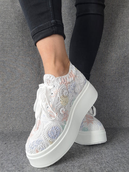 Sneakers plateforme dentelle brodée irisée aux reflets multicolores pastel, portées avec un jean noir