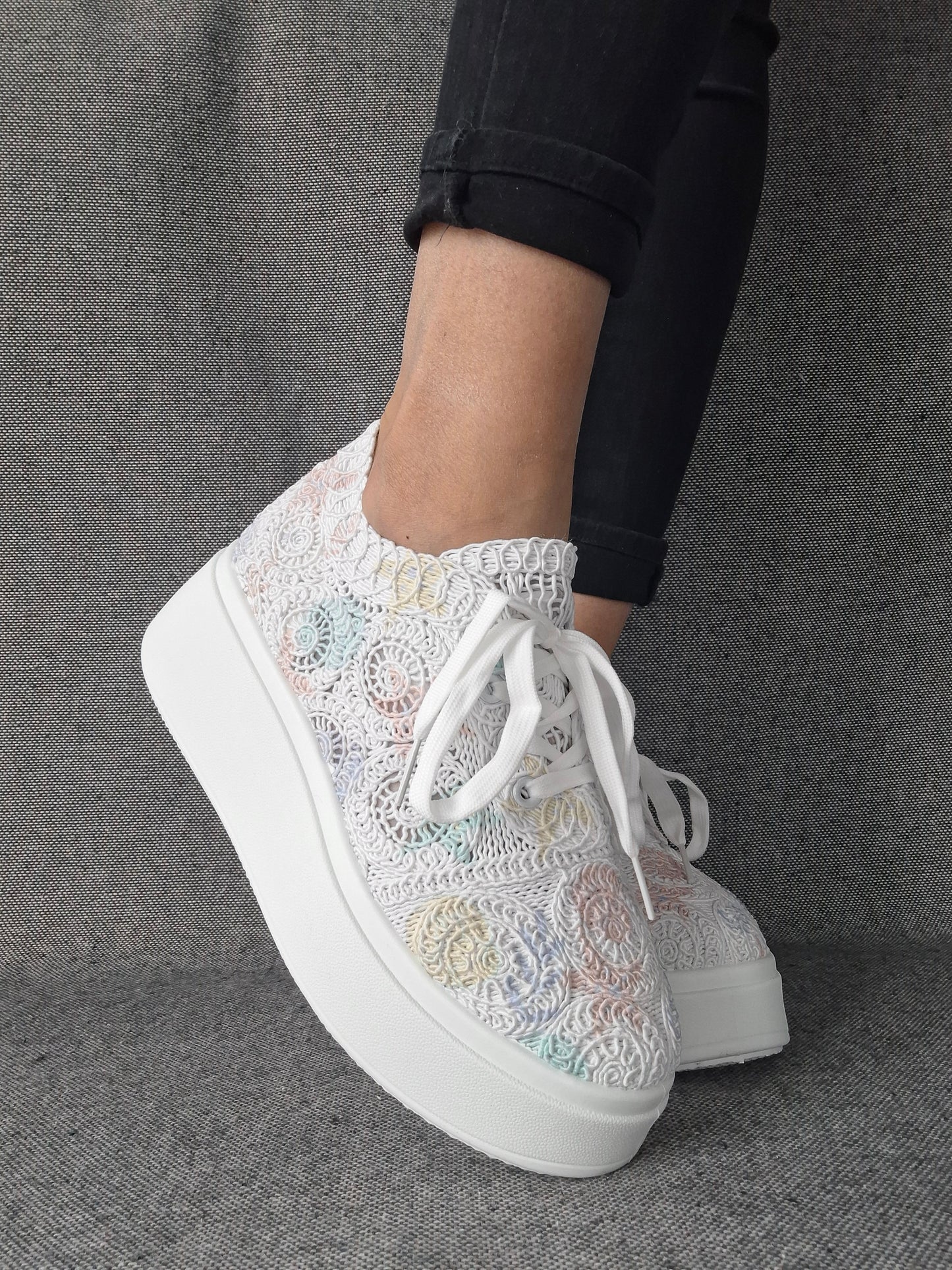 Sneakers plateforme dentelle brodée irisée aux reflets multicolores pastel, portées avec un jean noir