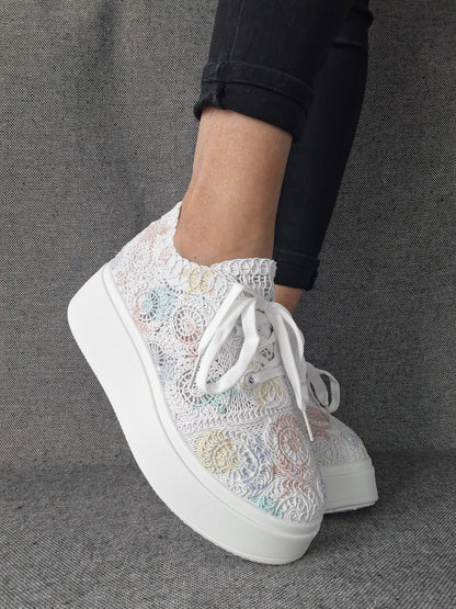 Sneakers plateforme dentelle brodée irisée aux reflets multicolores pastel, portées avec un jean noir