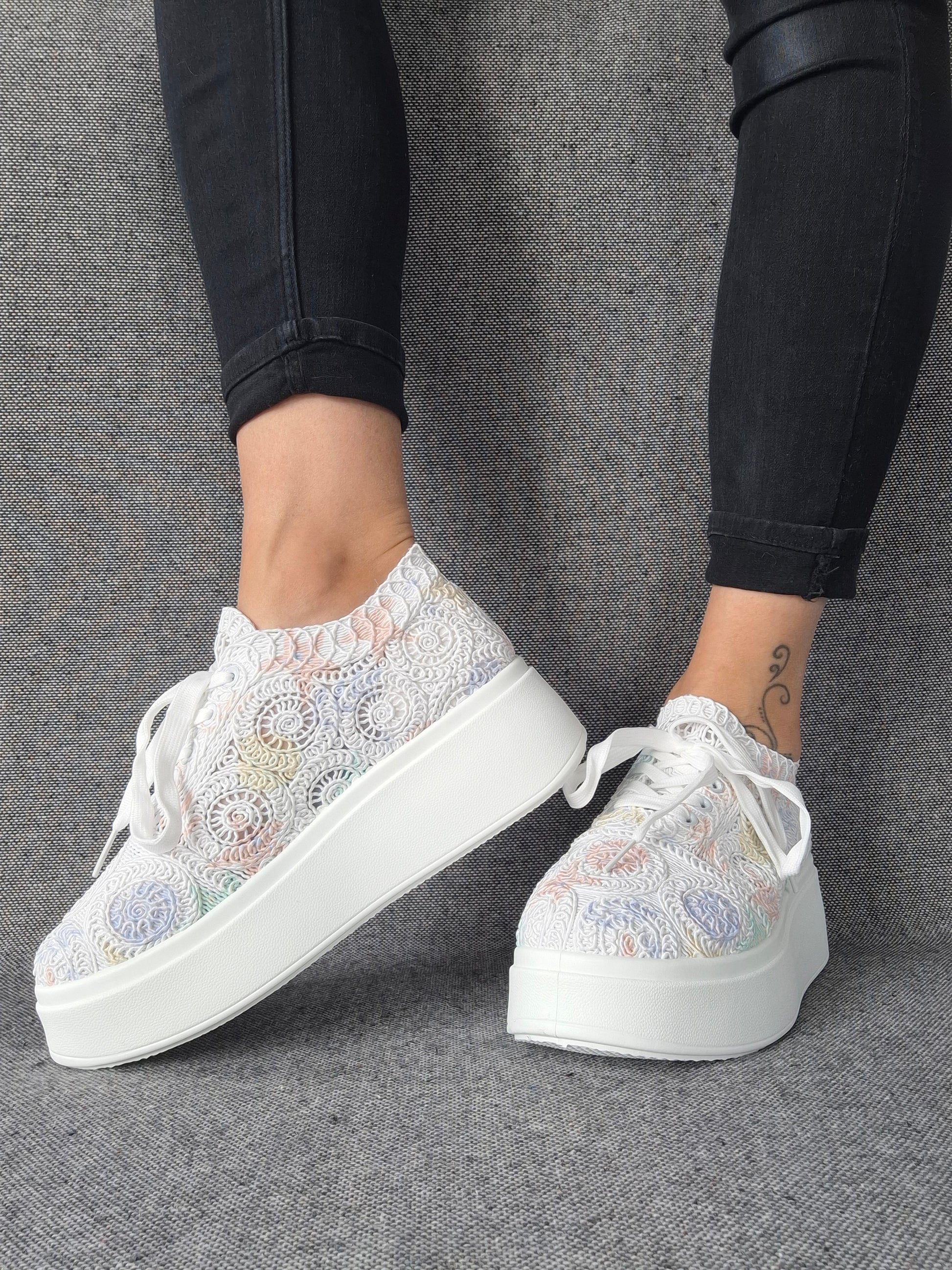 Sneakers plateforme dentelle brodée irisée aux reflets multicolores pastel, portées avec un jean noir