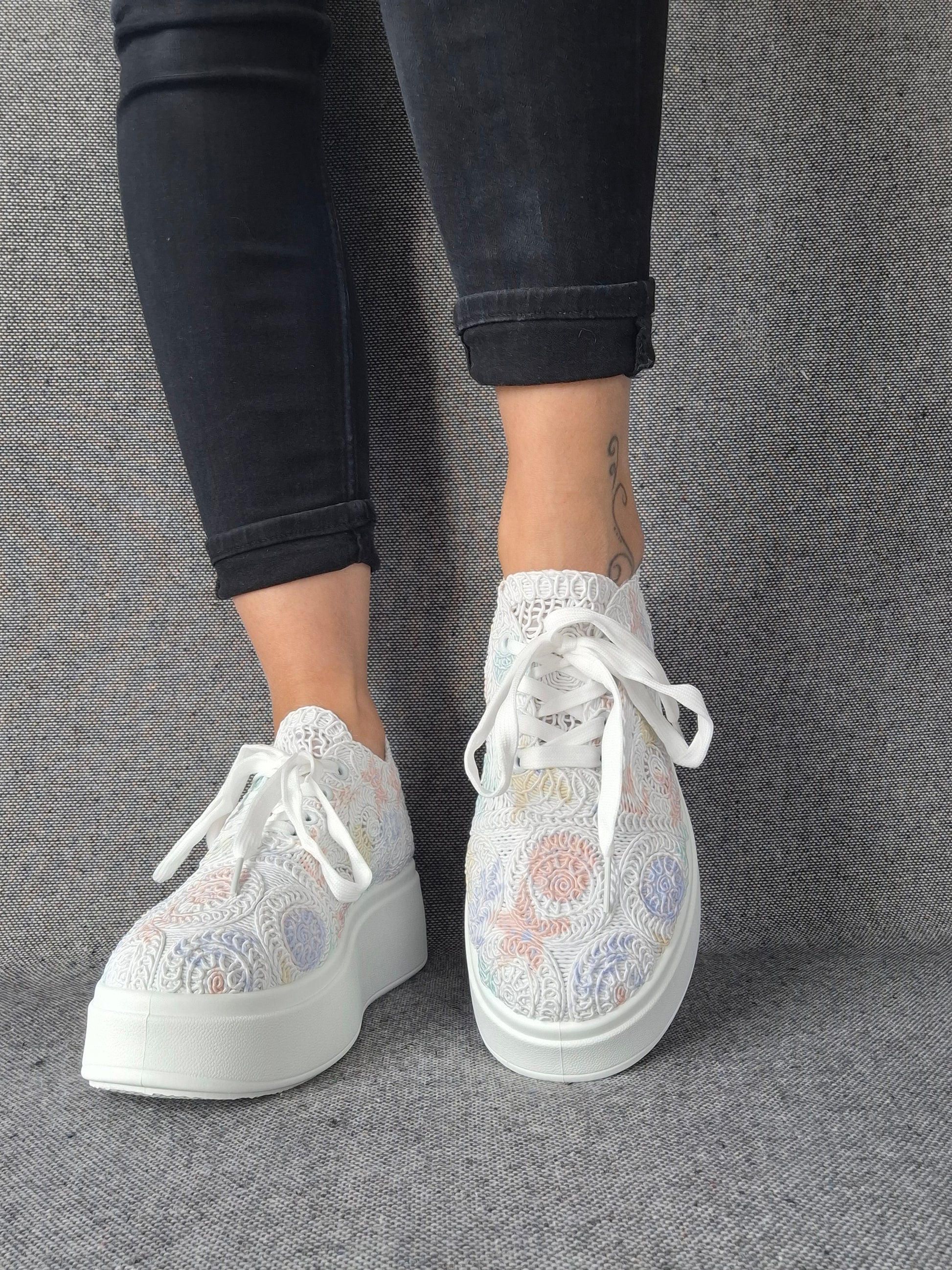 Sneakers plateforme dentelle brodée irisée à reflets multicolores portées avec un jean noir, semelle blanche épaisse