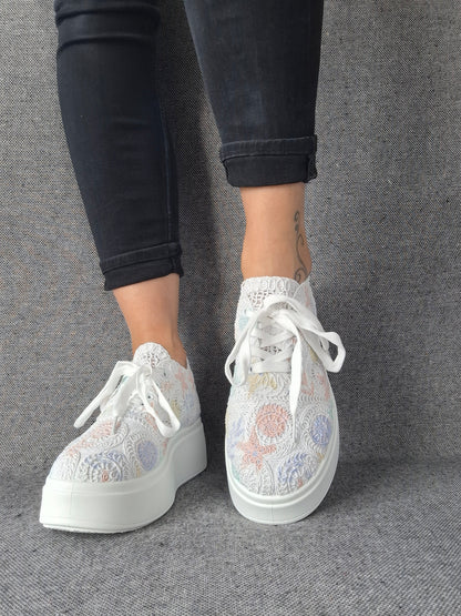 Sneakers plateforme dentelle brodée irisée à reflets multicolores portées avec un jean noir, semelle blanche épaisse