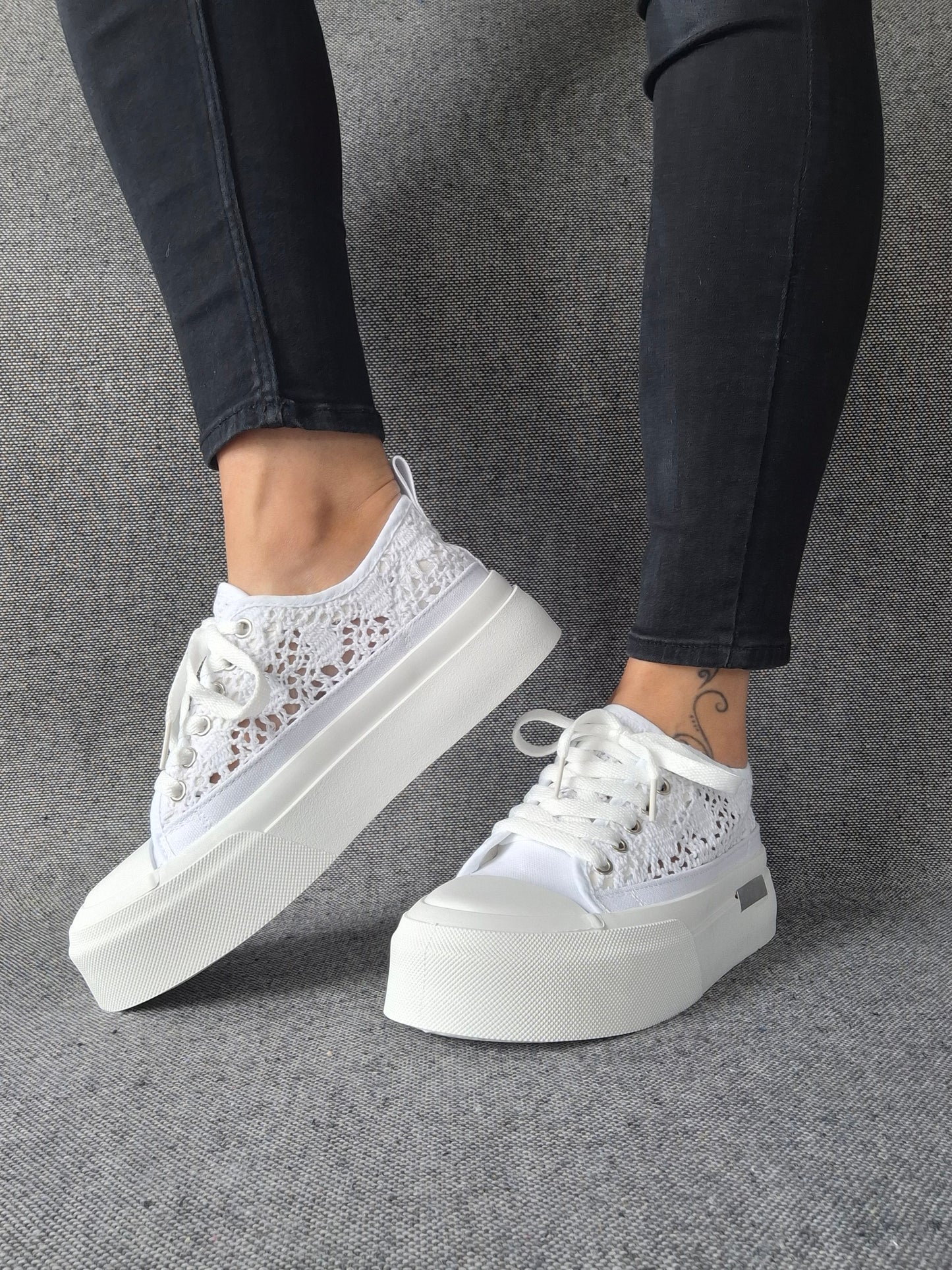 Sneakers blanches à plateforme en dentelle crochetée portées avec un jean gris, semelle compensée épaisse