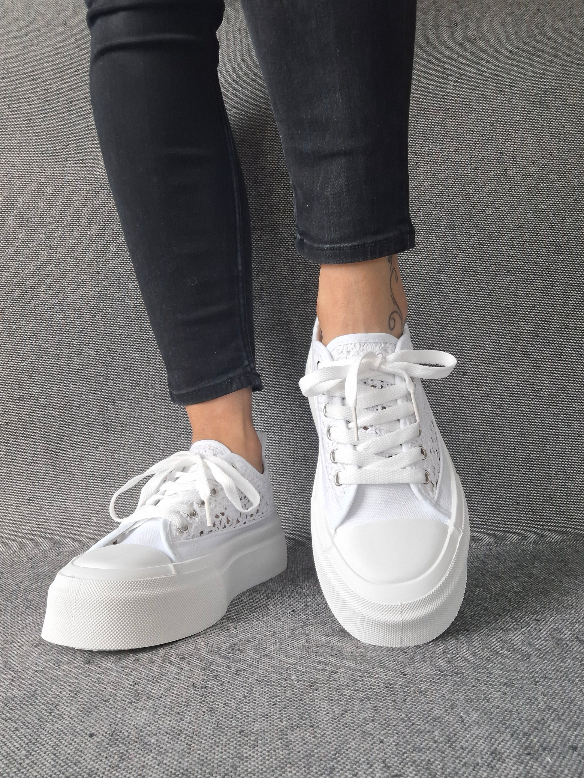 Sneakers blanches à plateforme en dentelle crochetée portées avec un jean gris, lacets blancs et semelle épaisse