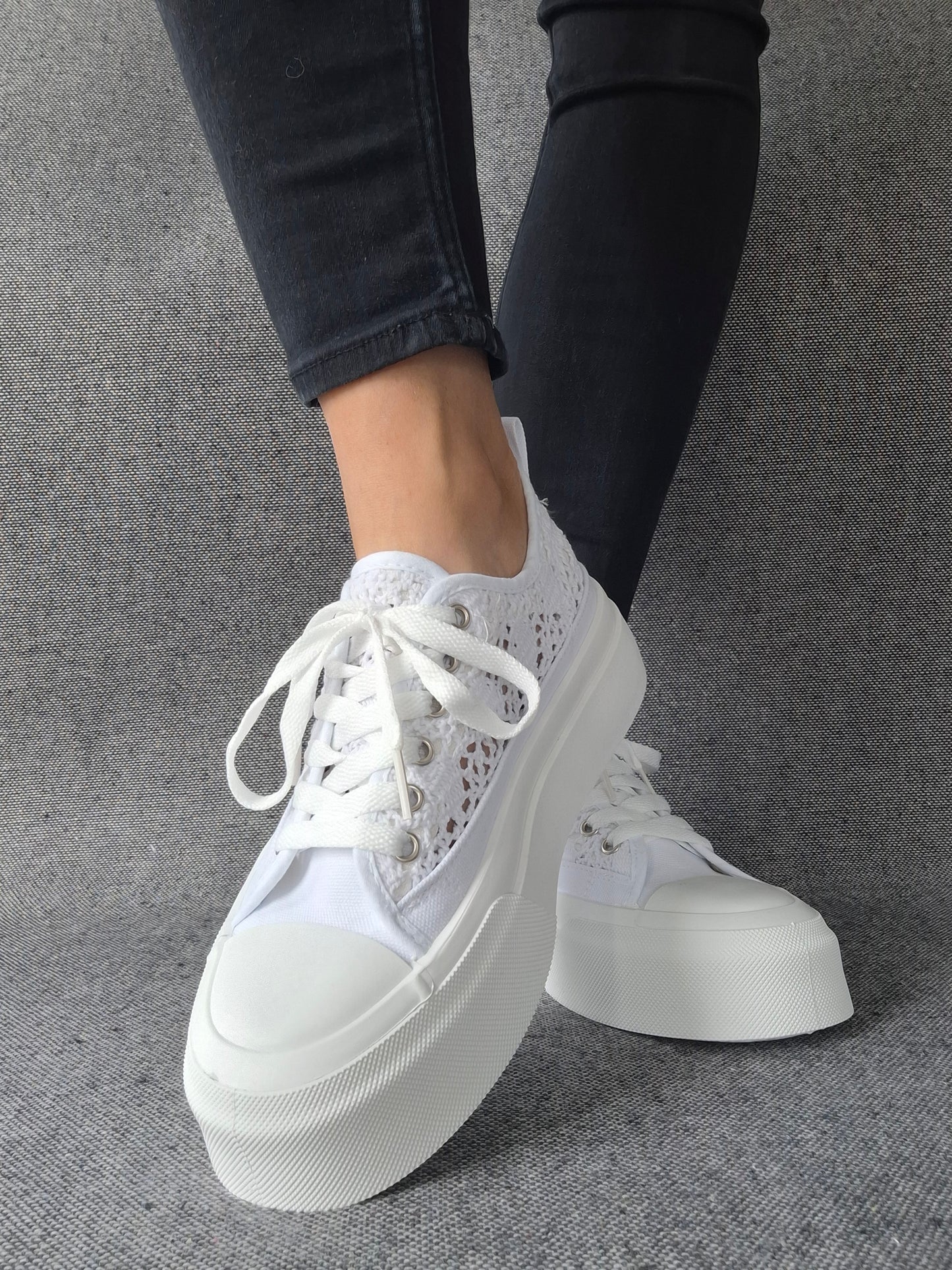 Sneakers blanches à plateforme en dentelle crochetée portées avec un jean gris, semelle épaisse et lacets blancs