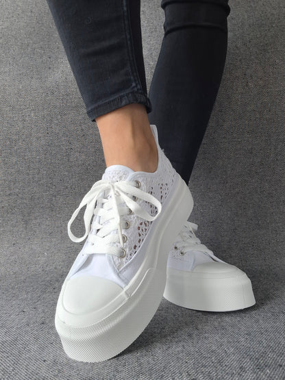 Sneakers blanches à plateforme en dentelle crochetée portées avec un jean gris, semelle épaisse et lacets blancs