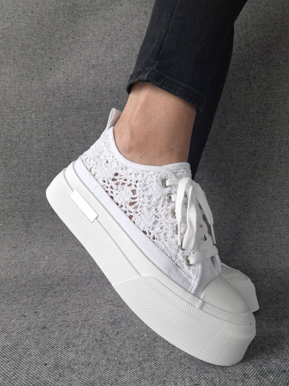 Sneakers blanches à plateforme en dentelle crochetée portées avec un jean noir, semelle épaisse et lacets blancs