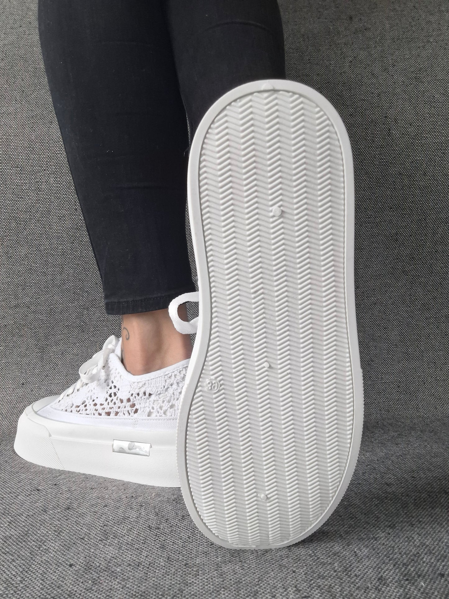 Semelle blanche texturée de sneakers blanches à plateforme en dentelle crochetée portées avec un jean noir