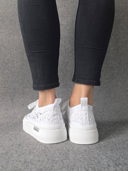 Vue arrière de sneakers blanches à plateforme en dentelle crochetée portées avec un jean noir