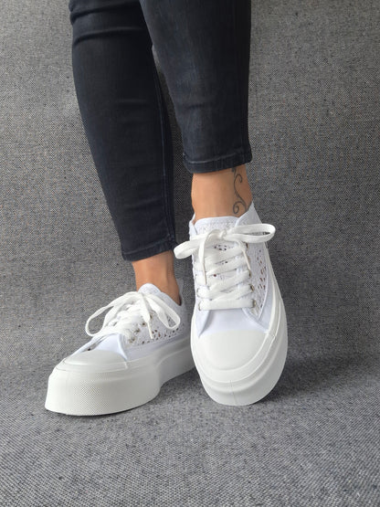 Sneakers blanches à plateforme en dentelle crochetée portées avec un jean noir, semelle épaisse et lacets blancs