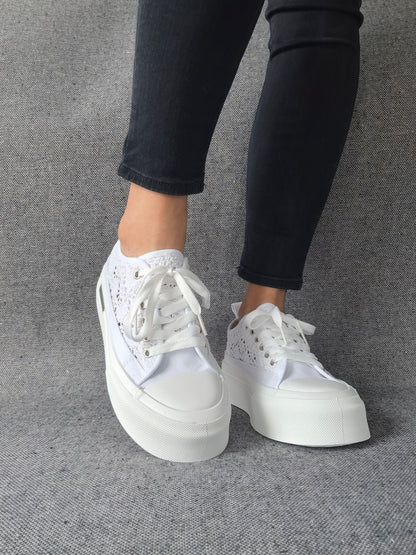 Sneakers blanches à plateforme en dentelle crochetée portées avec un jean noir, semelle épaisse et lacets blancs