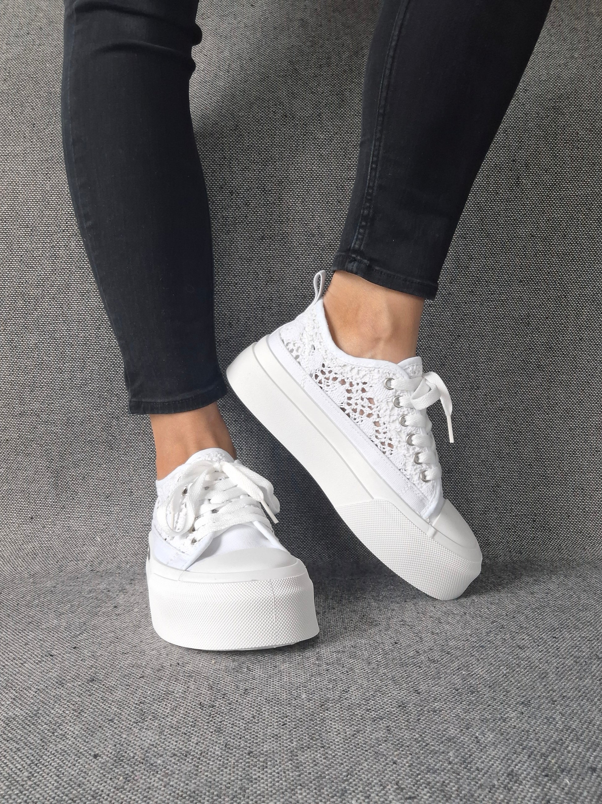 Sneakers blanches à plateforme en dentelle crochetée portées avec un jean noir, semelle épaisse et lacets blancs