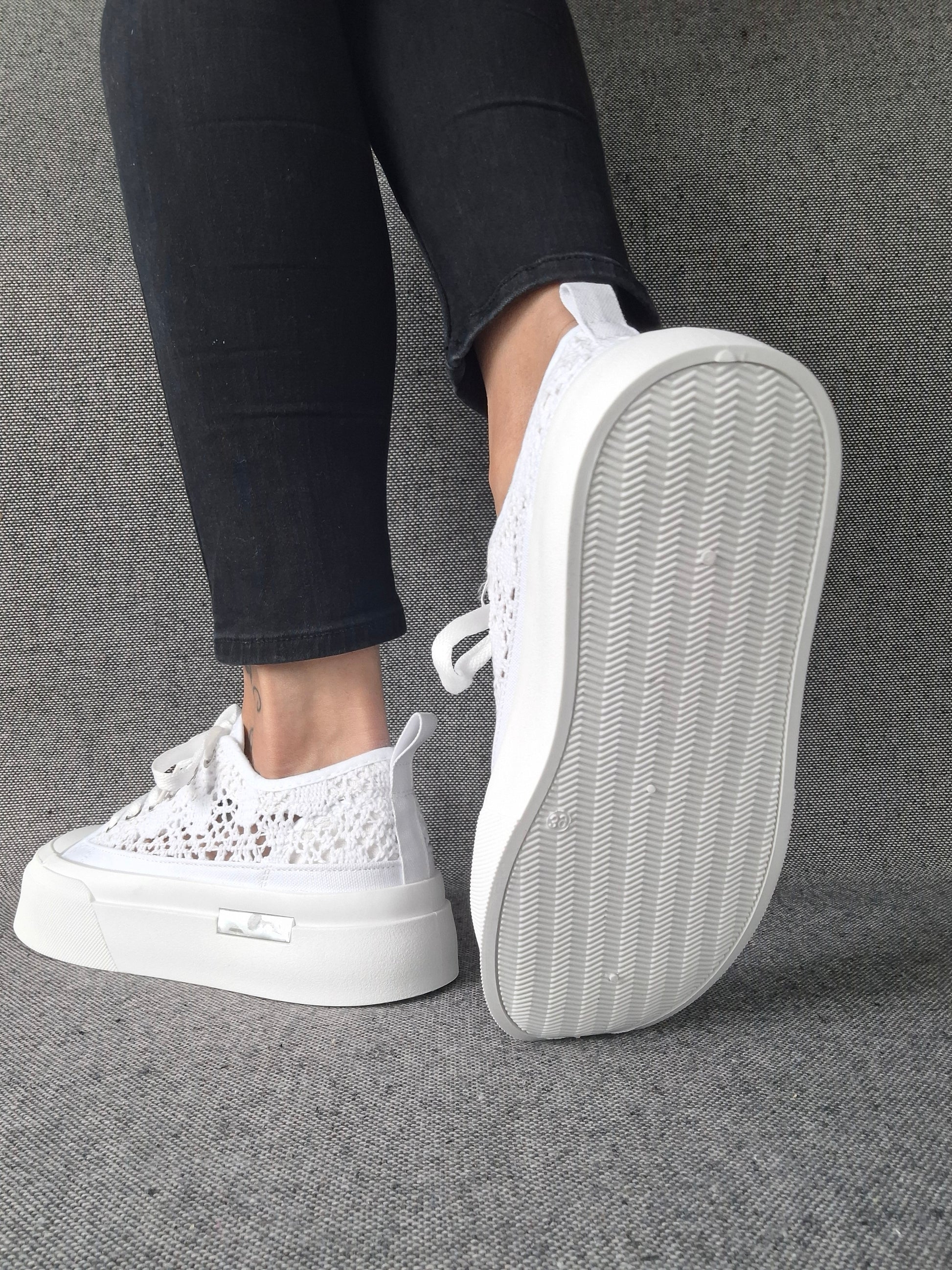Sneakers blanches à plateforme en dentelle crochetée portées avec un jean noir, semelle épaisse visible