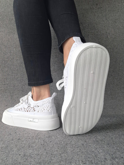 Sneakers blanches à plateforme en dentelle crochetée portées avec un jean noir, semelle épaisse visible