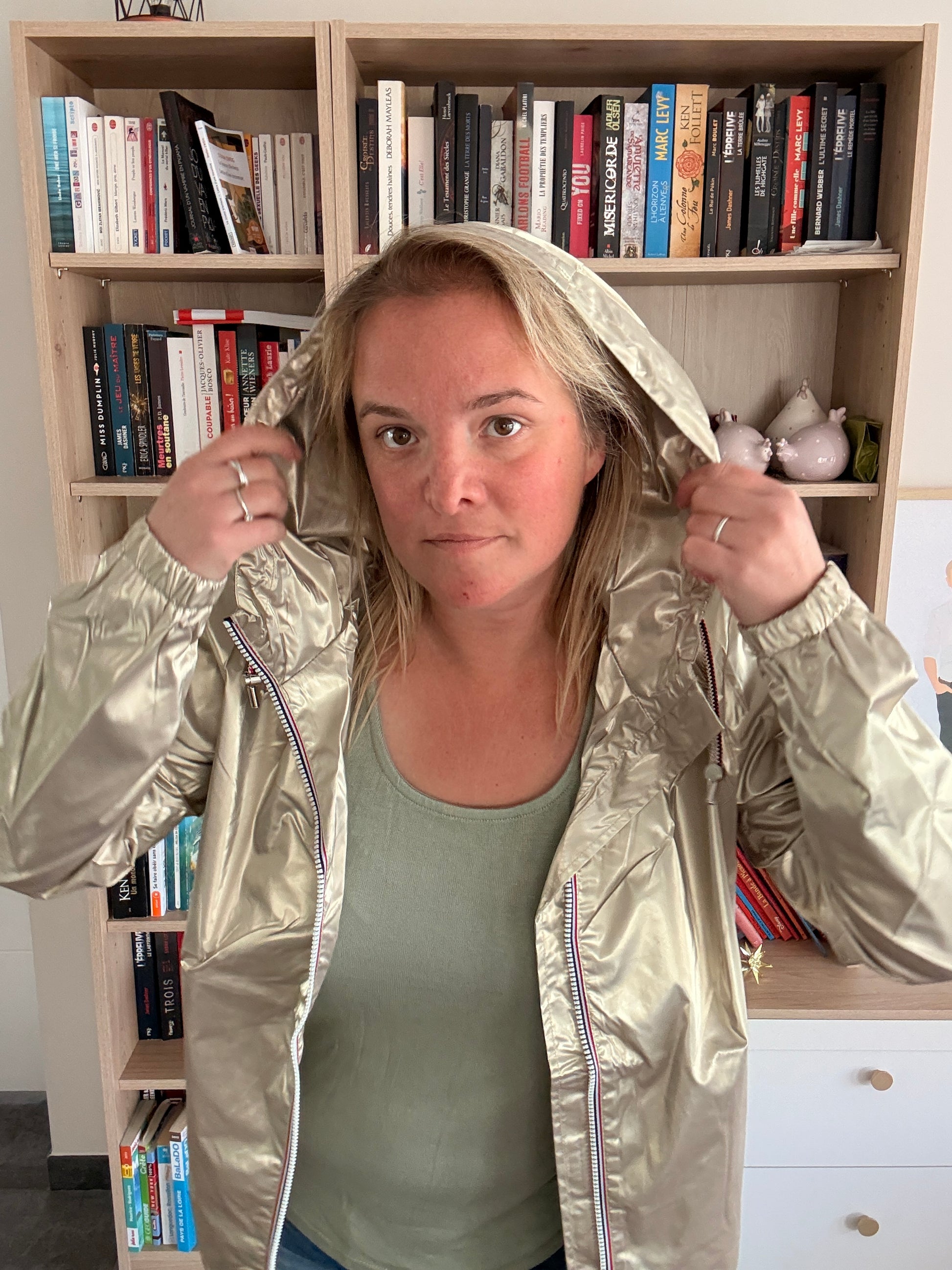 Femme montrant la capuche ajustable de la parka dorée Laura Jo, tenue à deux mains, zip tricolore visible