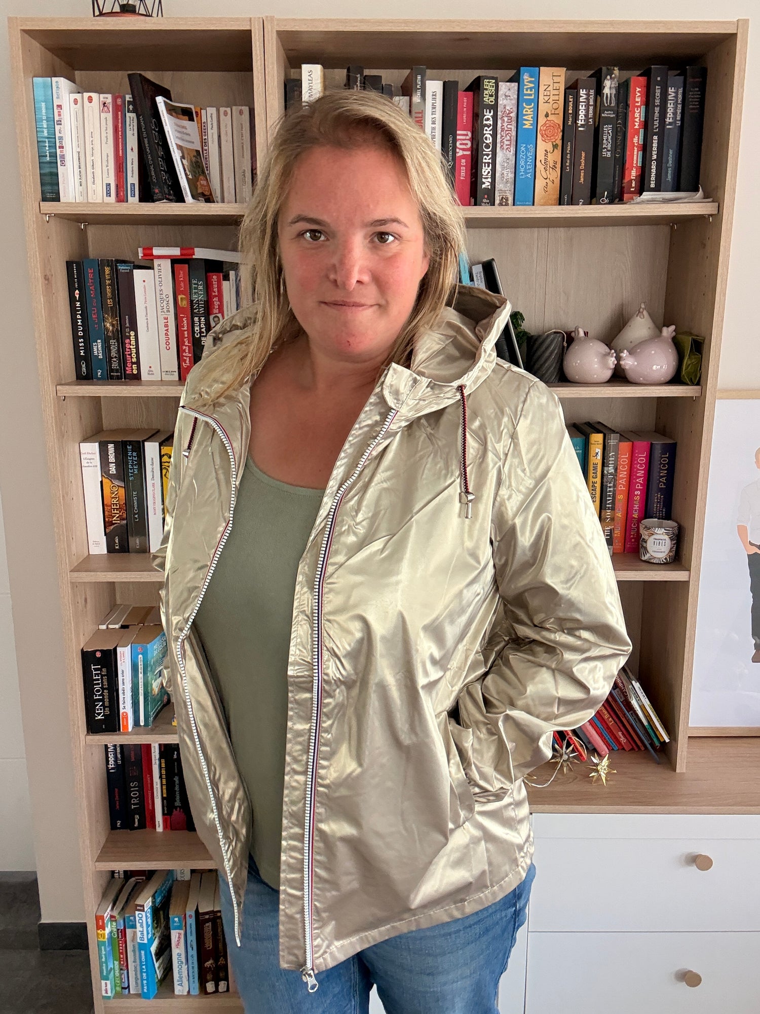 Femme portant la parka dorée Laura Jo vue de 3/4, main sur le zip tricolore, coupe légèrement cintrée visible