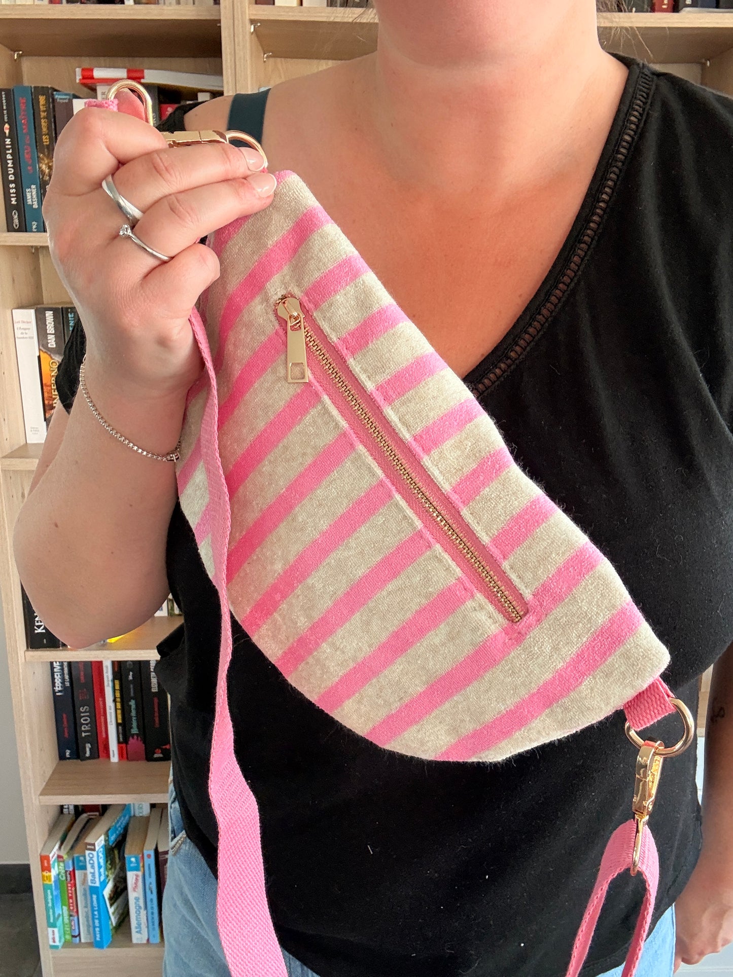 Dos du sac banane rayé rose avec poche zippée dorée tenu à la main