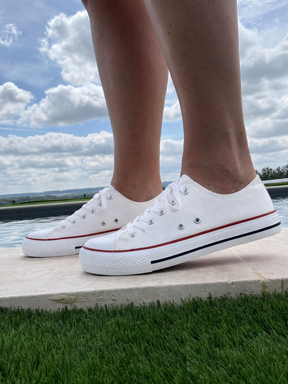 Baskets basses toile blanche style converse portées au bord d'une piscine – vue de côté

