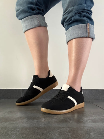 Baskets basses noires bande blanche femme style sneakers campus portées avec un jean retroussé, semelle caramel